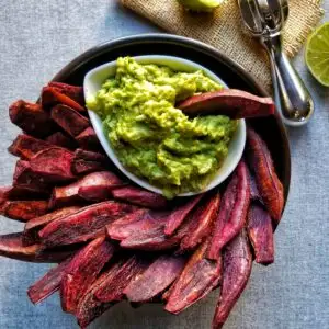 purple sweet potato wedges in a black bowl with guacamole
