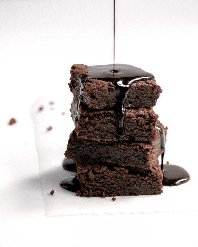 Vegan Brownies in a stack being drizzled with chocolate sauce