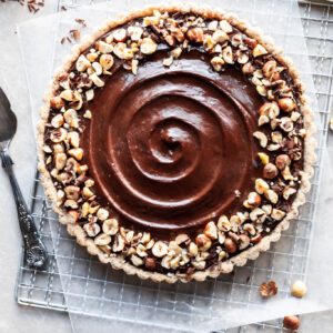 Flatlay of chocolate hazelnut tart on a cooling rack