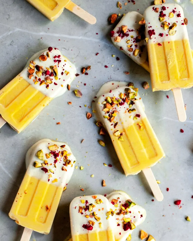 A marble counter with 8 light orange ice pops.