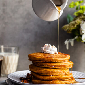 Stack of Pancakes on a plate being drizzled with maple syrup