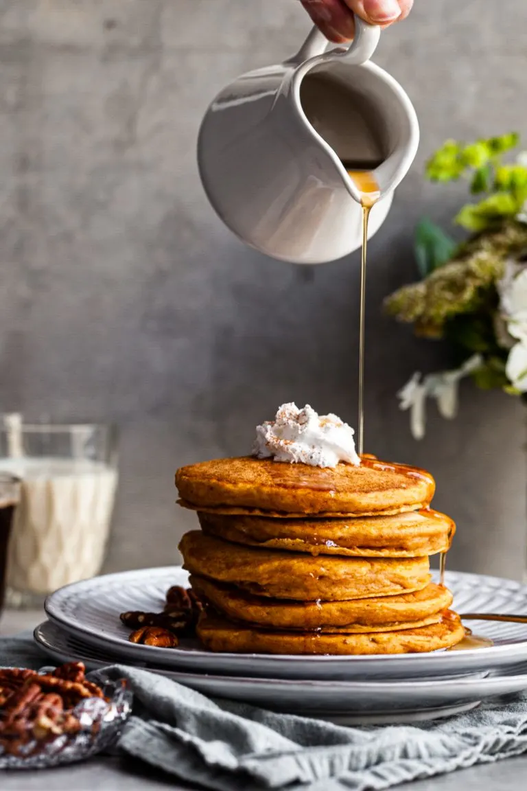 Stack of Pancakes on a plate being drizzled with maple syrup