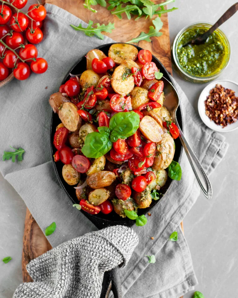 Roasted Baby Potatoes with Basil Pesto and Cherry Tomato Bruschetta being served with extra pesto and chilil flakes