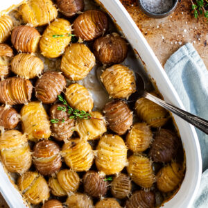 white casserole dish with hasselback cut baby potatoes in a creamy sauce
