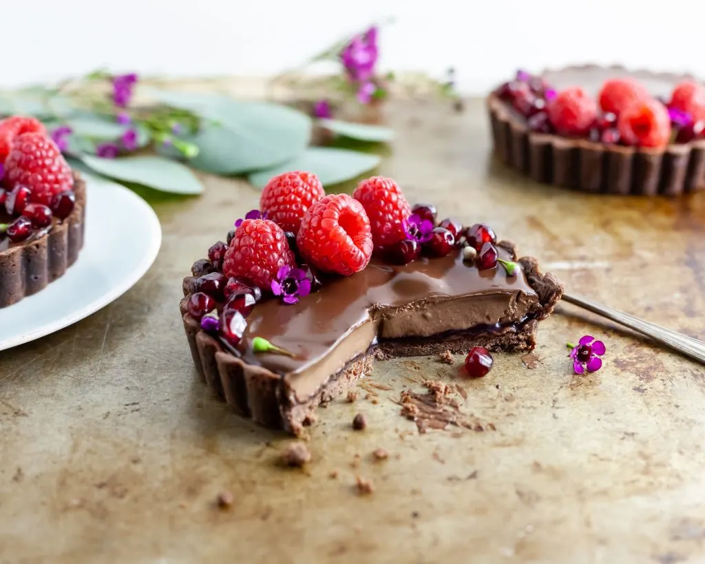 Chocolate Raspberry Dream Tart with a slice missing revealing the chocolate and raspberry layers