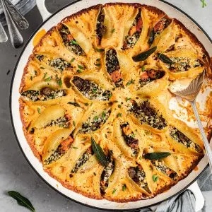 Round white skillet filled with pasta shells stuffed with butternut squash, vegan ricotta