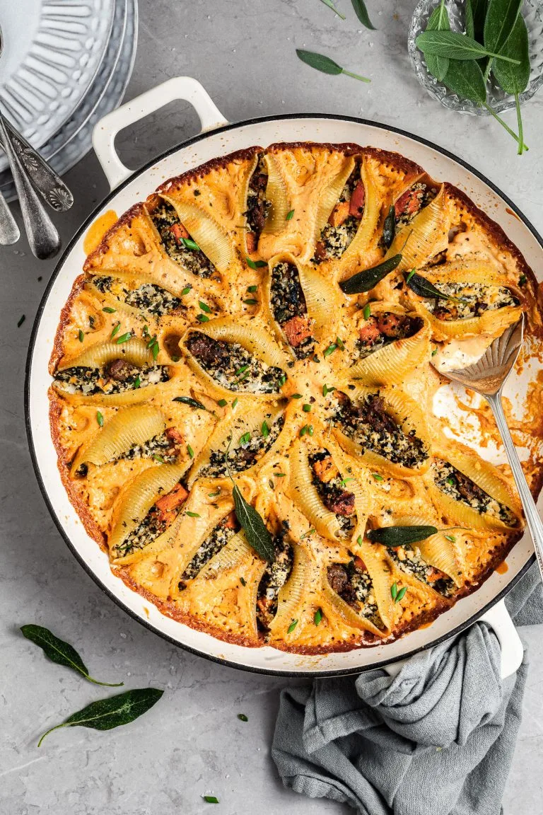 Round white skillet filled with pasta shells stuffed with butternut squash, vegan ricotta