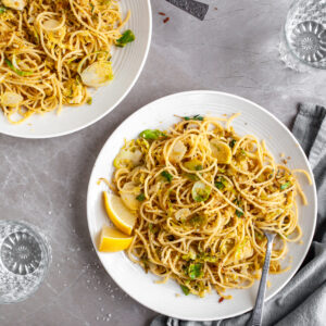 15 Minute Garlicky Breadcrumb Pasta with Shredded Brussels Sprouts served on white plates with chili flakes
