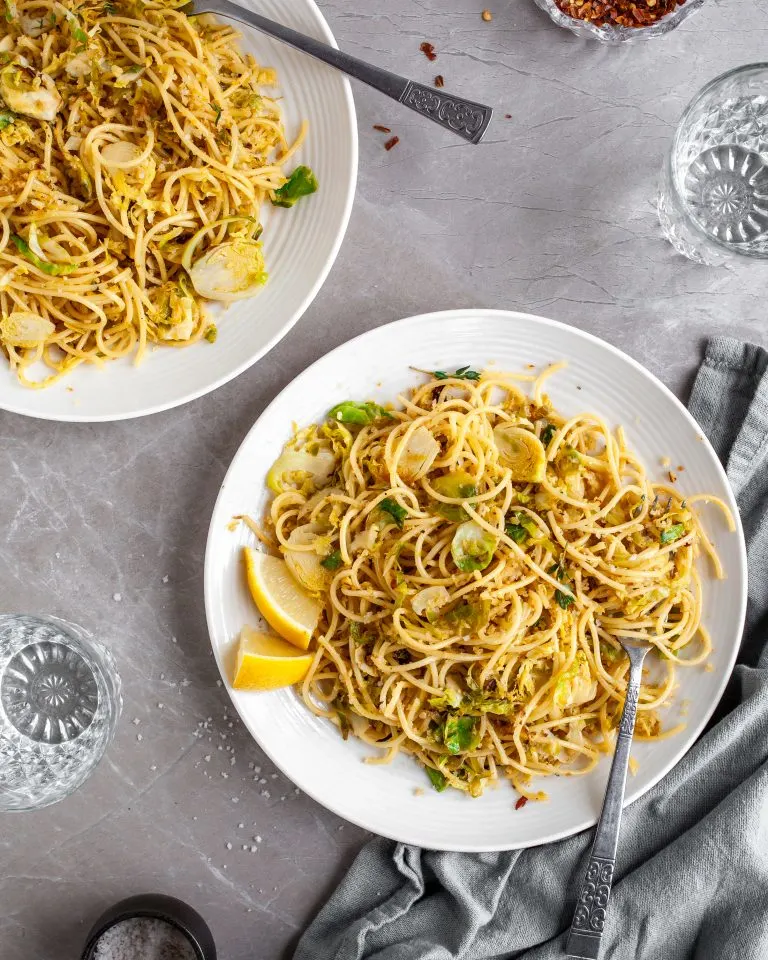 15 Minute Garlicky Breadcrumb Pasta with Shredded Brussels Sprouts served on white plates with chili flakes