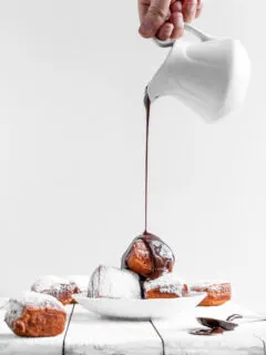 Vegan Beignets being covered in chocolate sauce