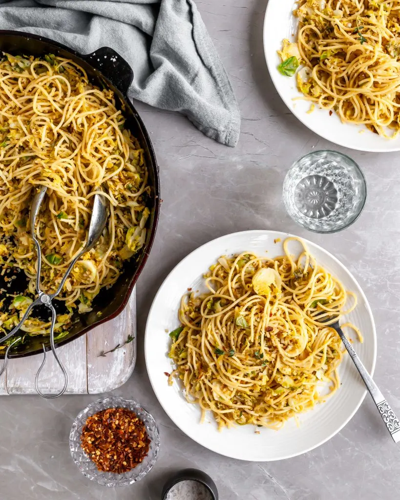 15 Minute Garlicky Breadcrumb Pasta with Shredded Brussels Sprouts being served from skillet onto white plates