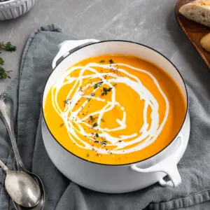 Creamy Curried Carrot, Ginger and Red Lentil Soup in pot with a swirl of coconut milk