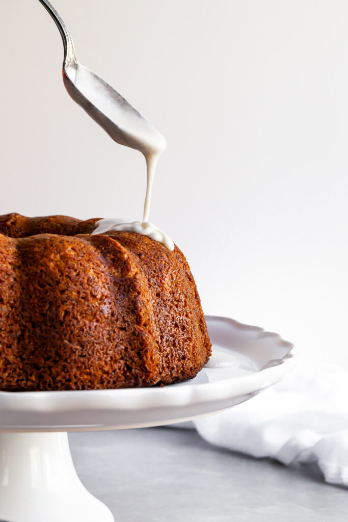 Vegan Hummingbird Cake being drizzled with vanilla glaze