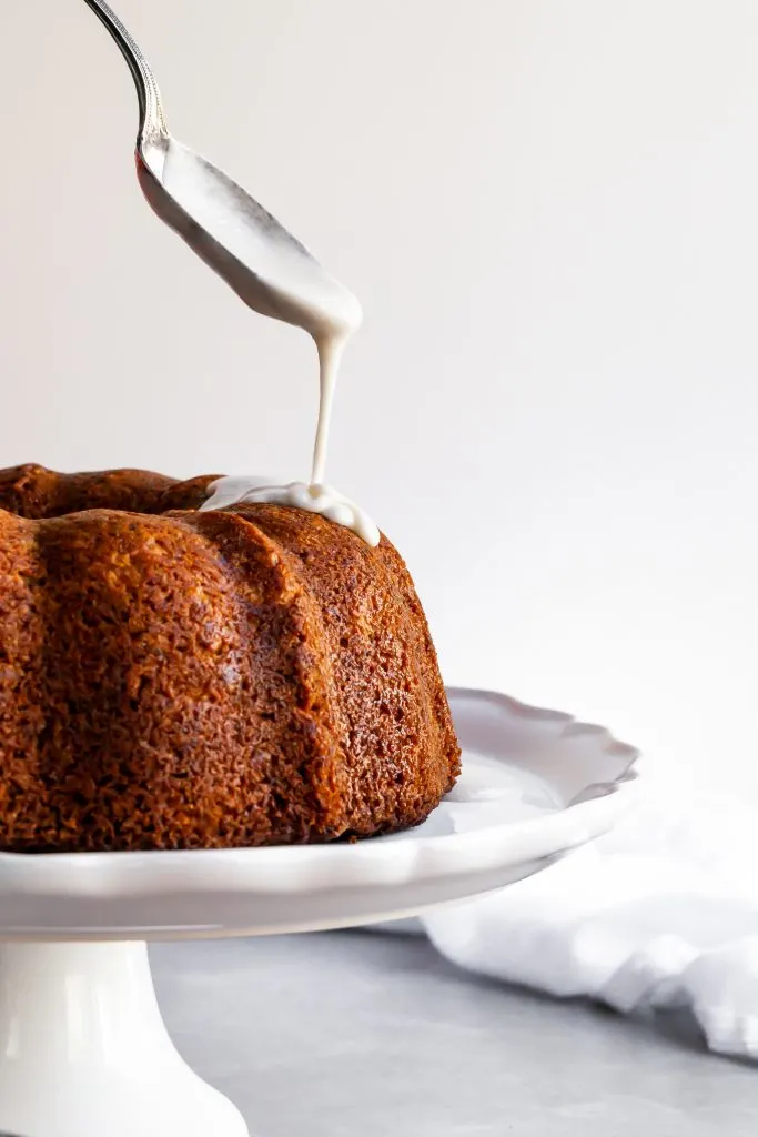 Vegan Hummingbird Cake being drizzled with vanilla glaze