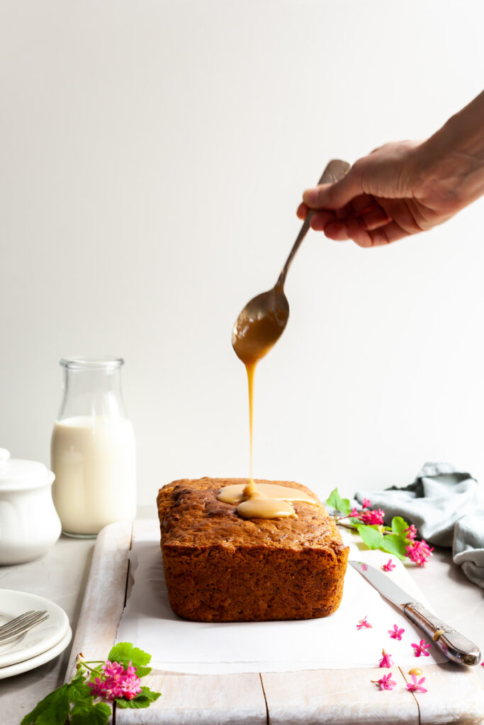 Vegan Carrot Spice Loaf with maple glaze being poured over the top