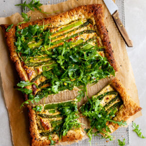 Vegan Asparagus and Pesto Cashew Cheese Tart with Lemon Arugula on colling rack and 2 pieces cut