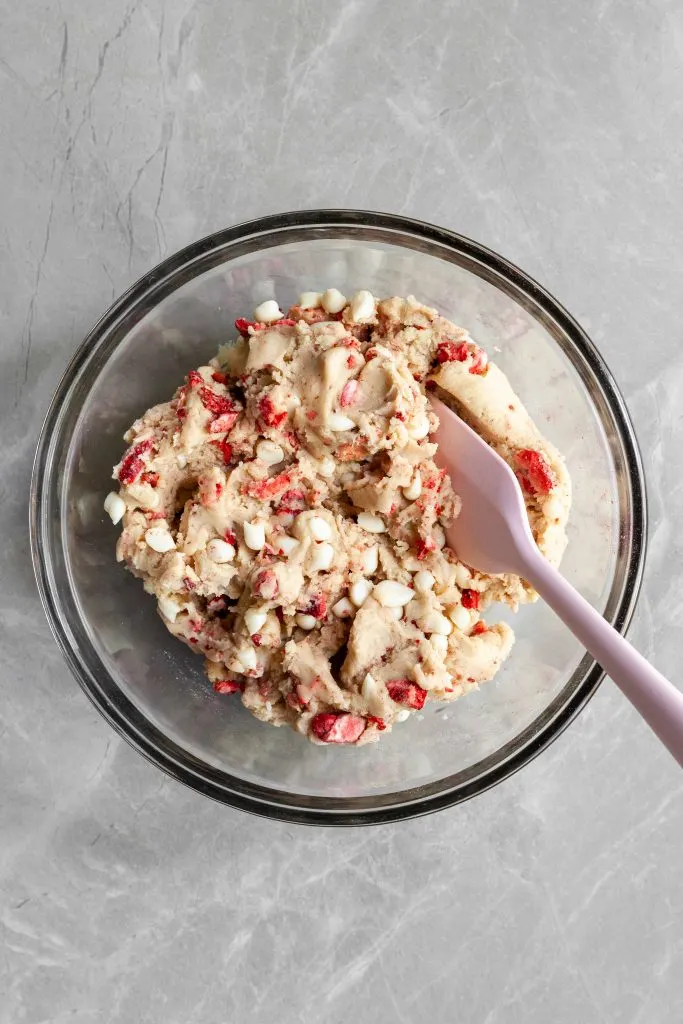 Strawberries and cream cookie dough in a bowl with a pink spatula