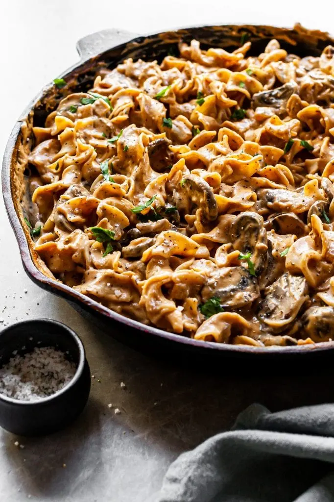 Side view of mushroom stroganoff in cast iron skillet, highlighting the creamy sauce