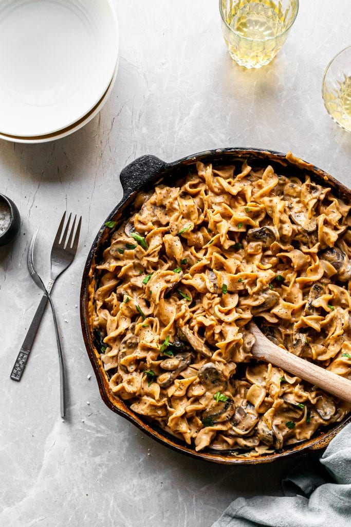 Mushroom Stroganoff in Cast Iron Skillet, ready to serve in white bowls