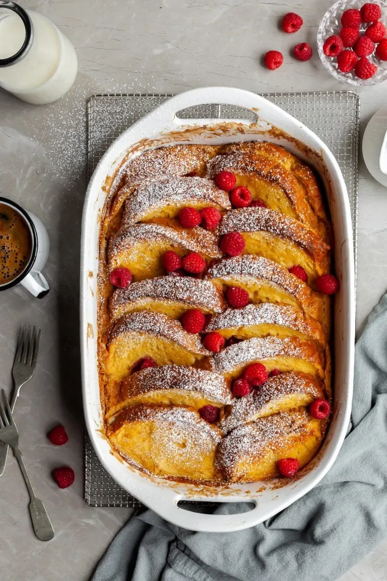 Vegan Lemon Raspberry French Toast Bake in white baking dish, garnished with fresh raspberries