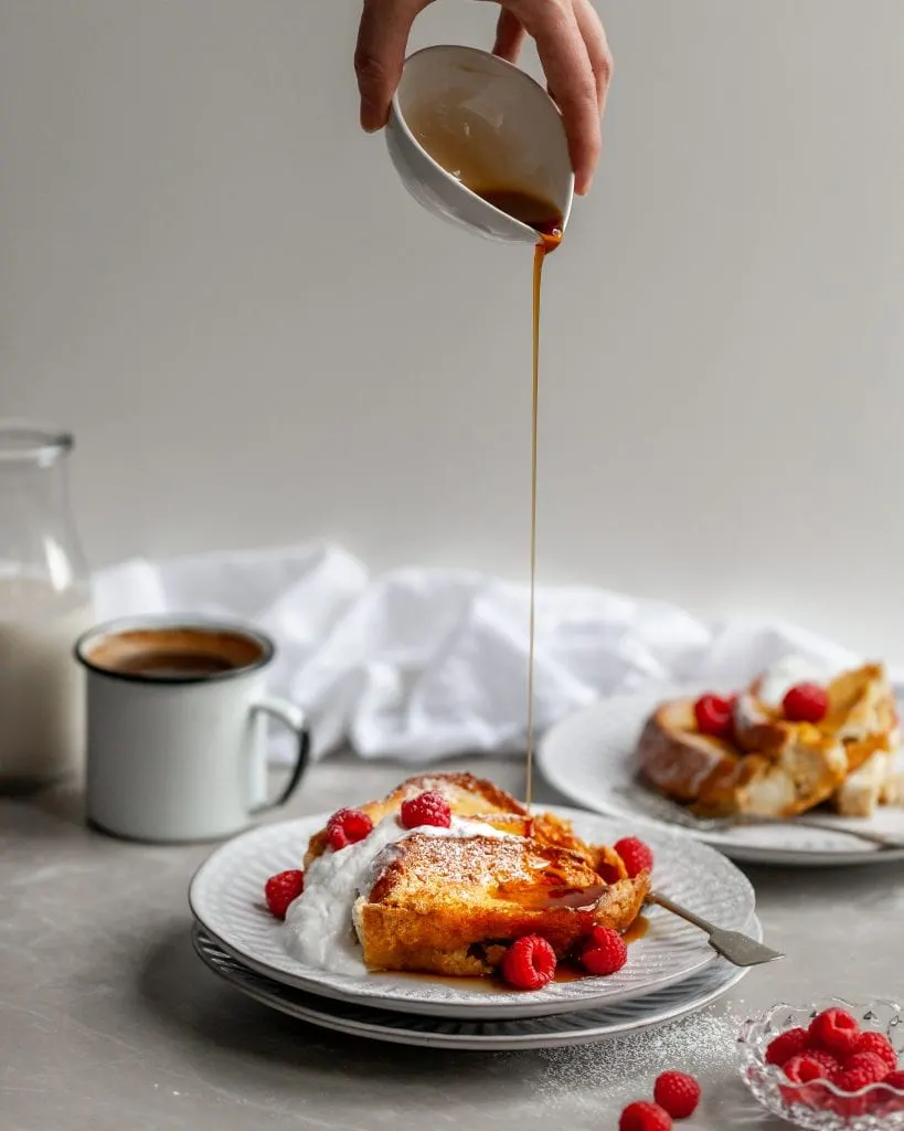 Overnight Vegan Lemon Raspberry French Toast served on a white plate and being drizzled with maple syrup