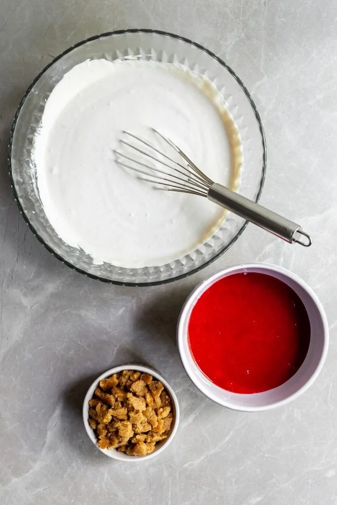 Prepared cashew base for the the ice cream in a large bowl, strawberry rhubarb sauce in a medium bowl and the crumbles in a small bowl