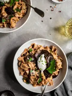 Mushroom Stroganoff served in white bowls, arnished with almond ricotta and parsley