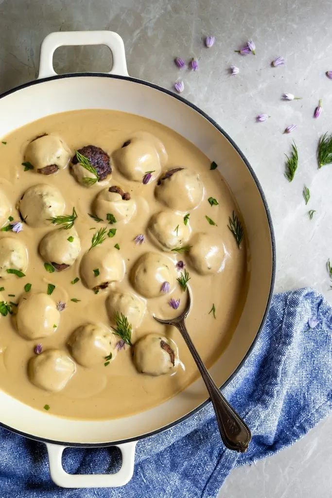 White skillet with swedish meatballs bathing in creamy swedish gravy