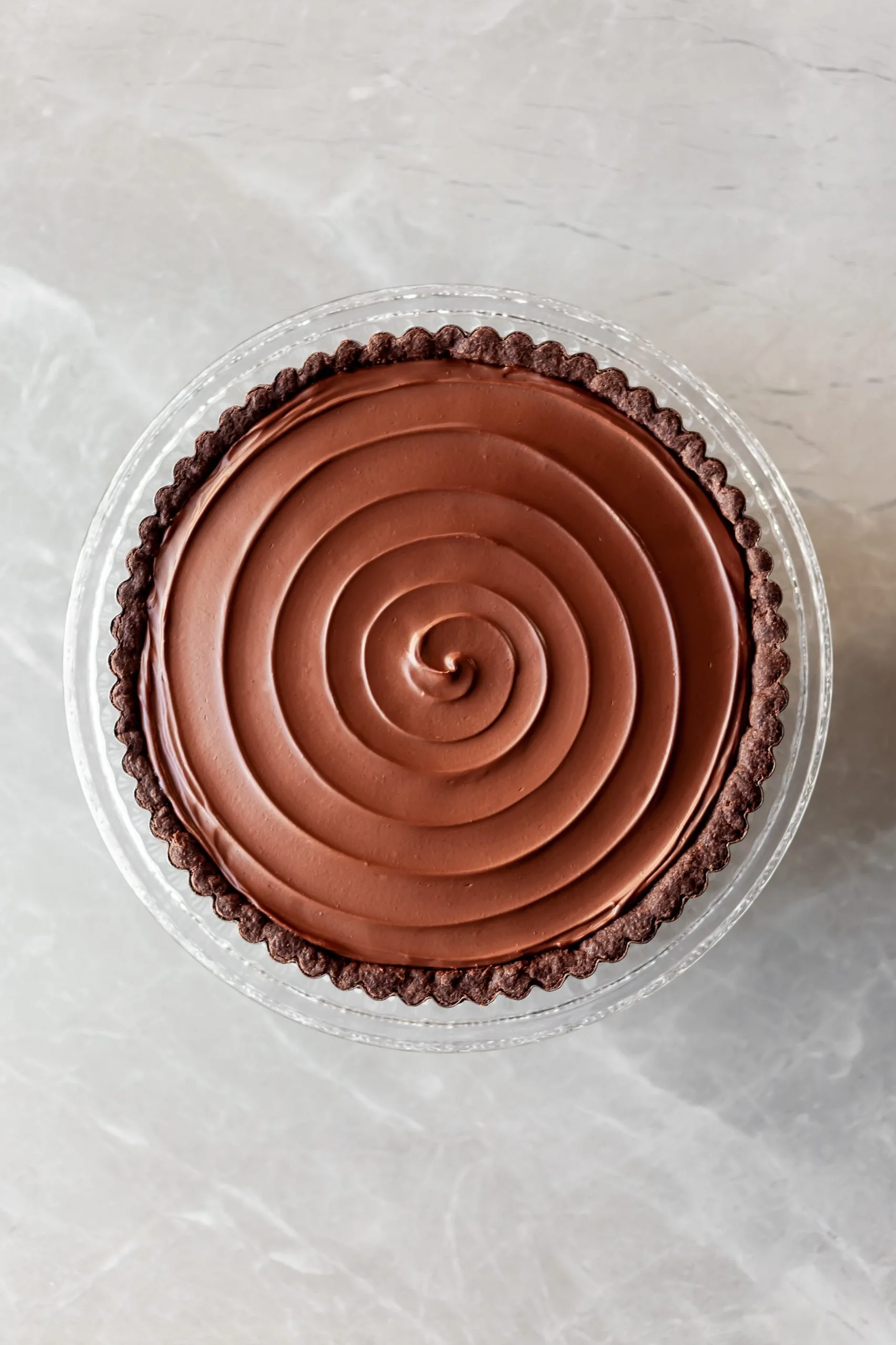 Vegan Chocolate Orange Tart with a swirl through the ganache on top prior to the candied kumquats being placed