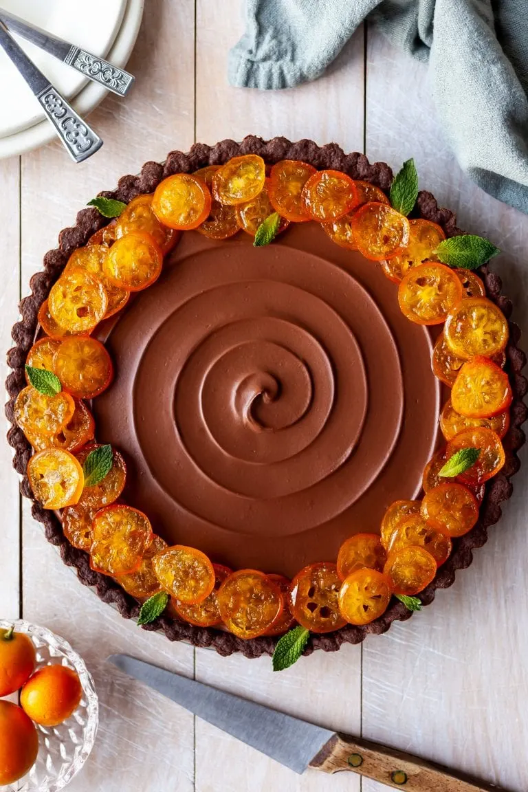 Flatlay of Vegan Chocolate Orange Tart with Candied Kumquats, ready to be sliced and served