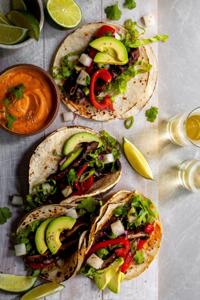 Looking down on 4 Korean Portobello Tacos served with lime wedges and Gochujang Crema