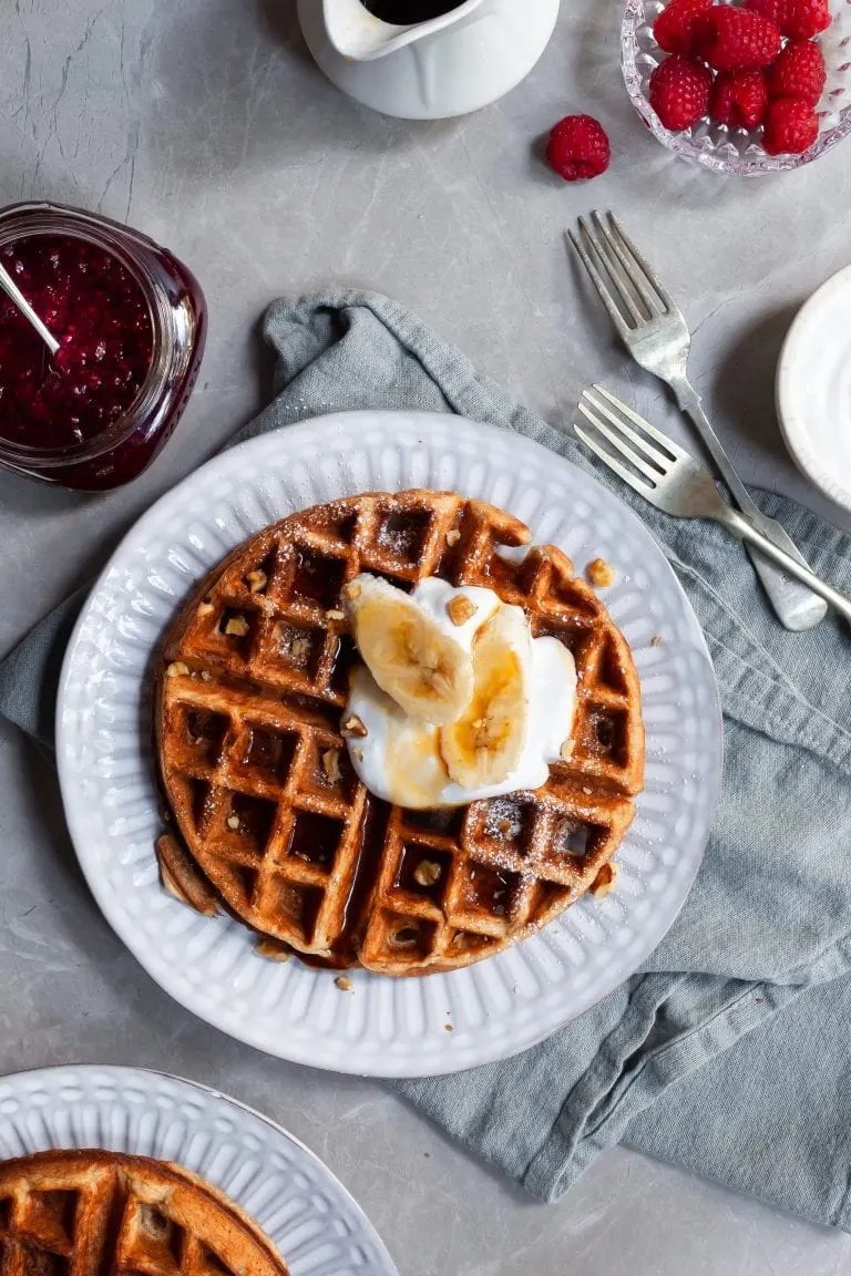 Vegan Banana Waffle on breakfast table served with fresh bananas and maple syrup
