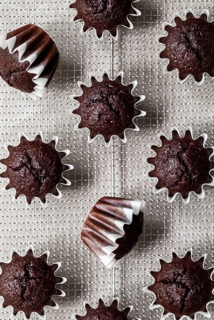 Unfrosted cupcake bases on a cooling rack, view from above