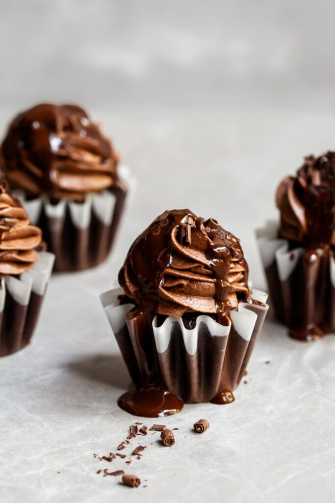 4 frosted chocolate cupcakes drizzled with chocolate ganache and chocolate shavings