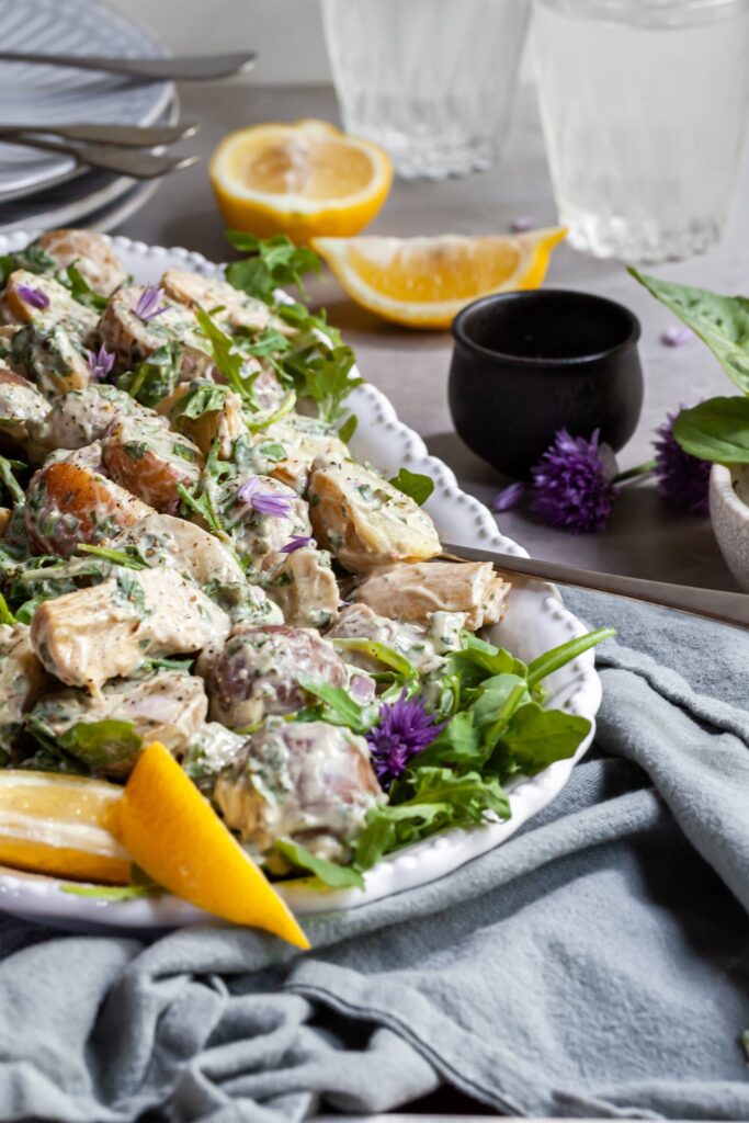 Side view of platter of creamy potato salad with basil and artichokes