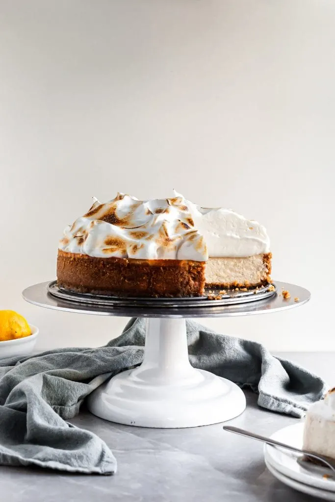 Vegan Lemon Meringue Baked Cheesecake with a slice missing, showing the creamy interior