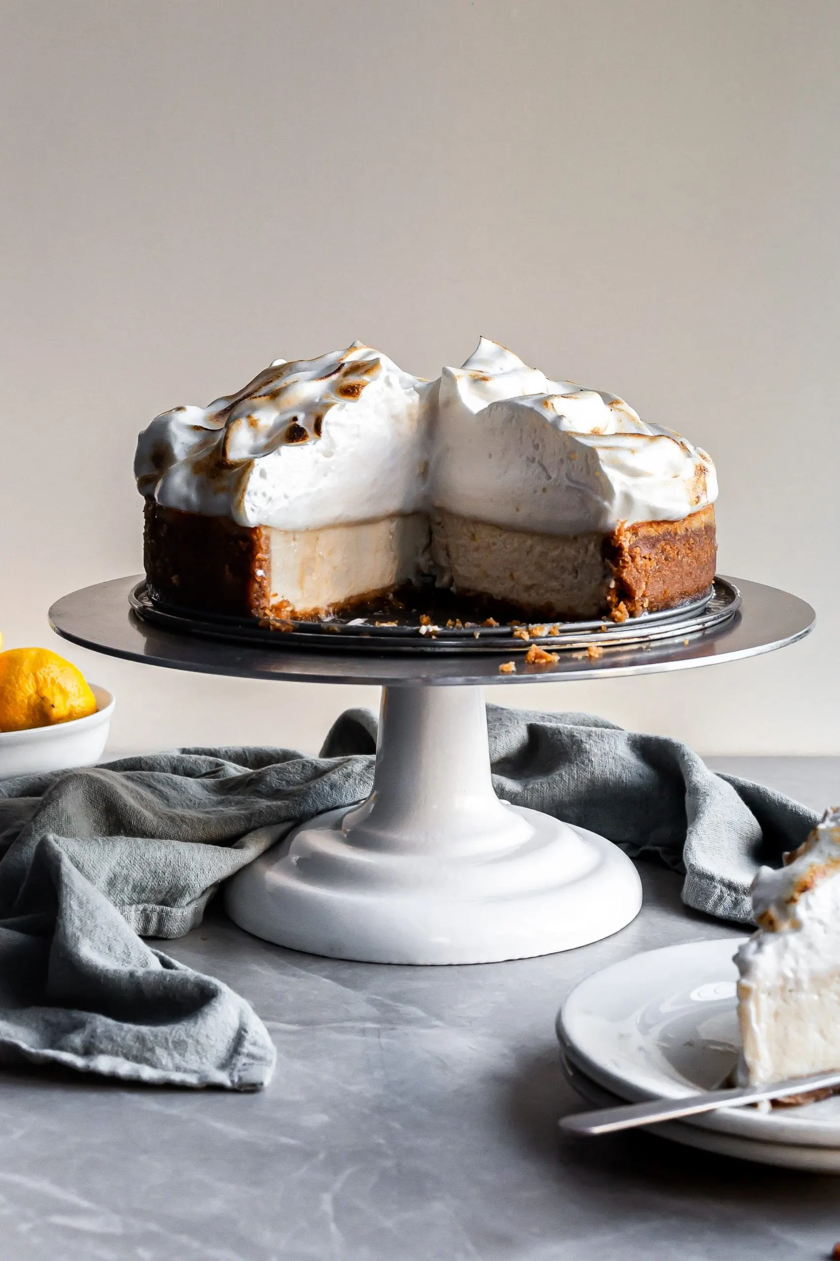 Vegan Lemon Meringue Baked Cheesecake with 2 slices missing showing the creamy interior and the pillowy meringue