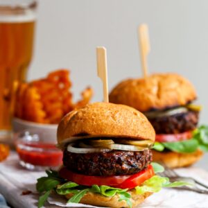 Vegan burger served in a toasted bun with pickles, sliced onions, lettuce and tomatoes.