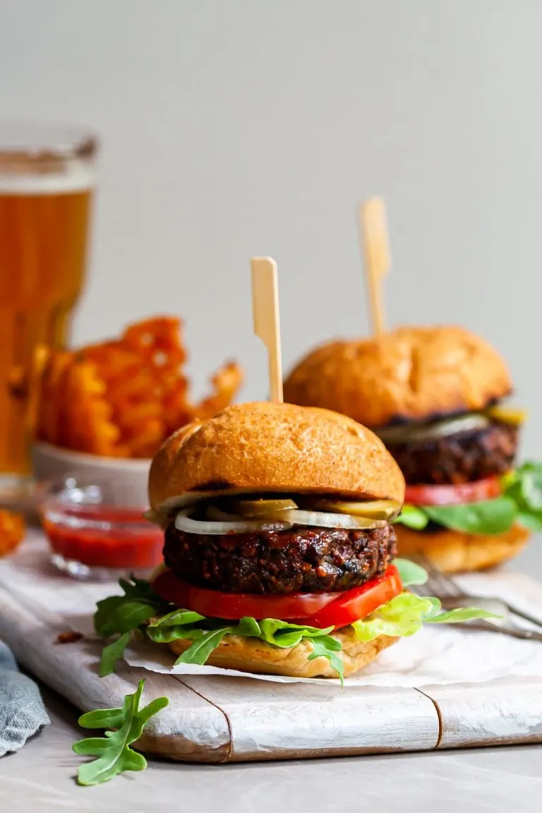 Vegan burger served in a toasted bun with pickles, sliced onions, lettuce and tomatoes.