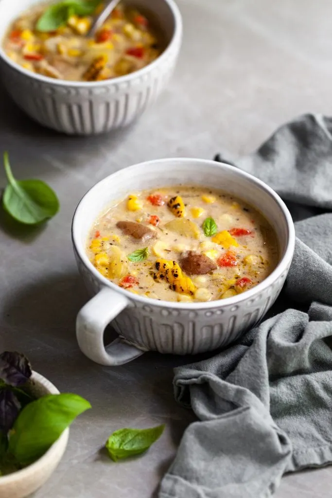 two large white mugs filled with  vegan corn and potato chowder