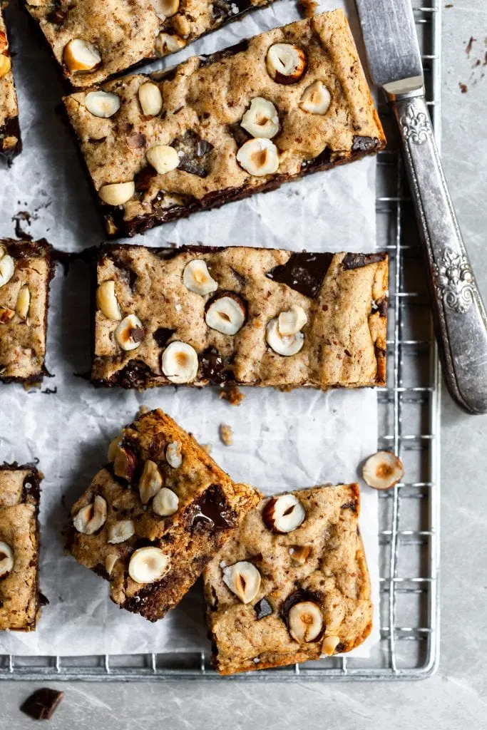 Close up of 3 sqaures of blondies on a cooling rack beside a silver knife