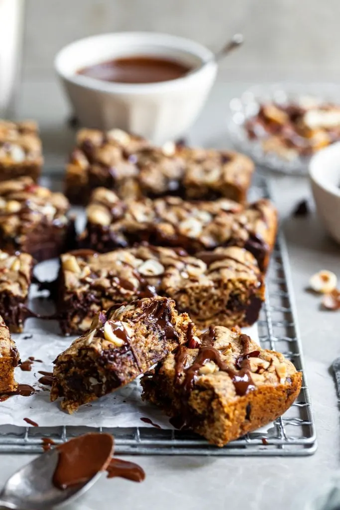 45 degree angle view of 2 blondie squares in foreground and glass of milk in background