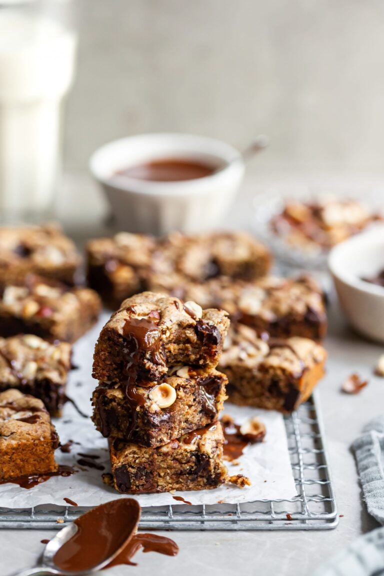 Stack of 3 vegan chocolate chunk blondies with more in the background on cooling rack