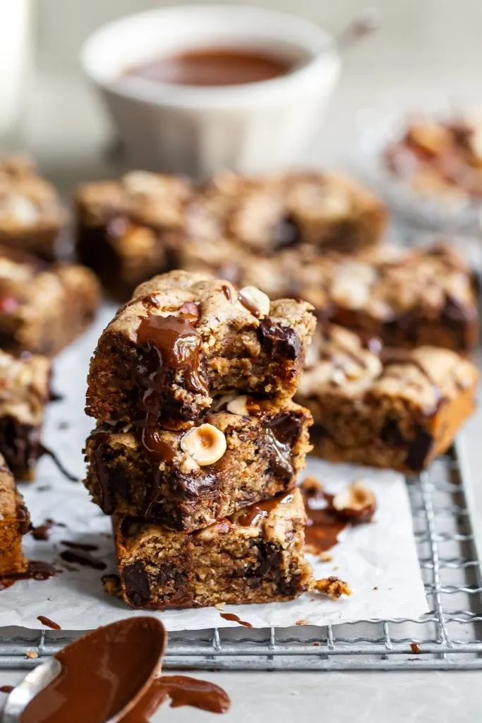 3 Vegan Chocolate Chunk Blondies stacked with a bite taken out of the top one