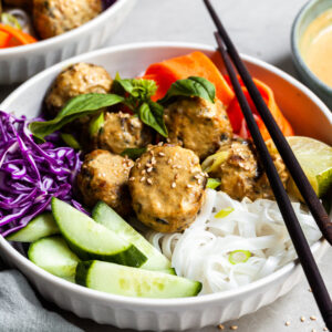 Thai inspired bowl of rice noodles with fresh veggies, chcikpea meatballs and coconut curry sauce