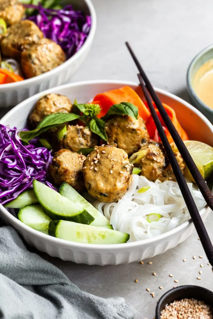 Thai inspired bowl of rice noodles with fresh veggies, chcikpea meatballs and coconut curry sauce