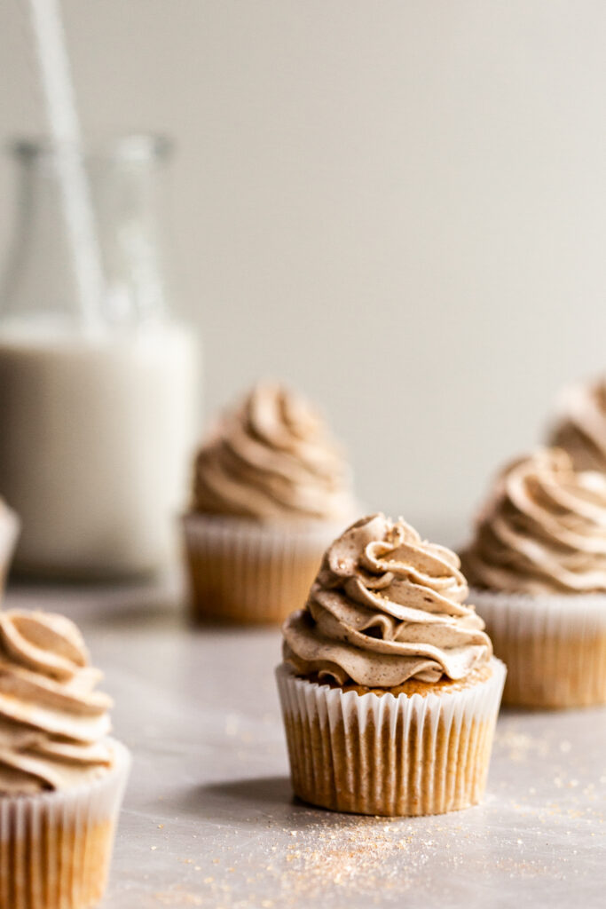 Frosted cupcakes on marble surface covered in cinnamon sugar