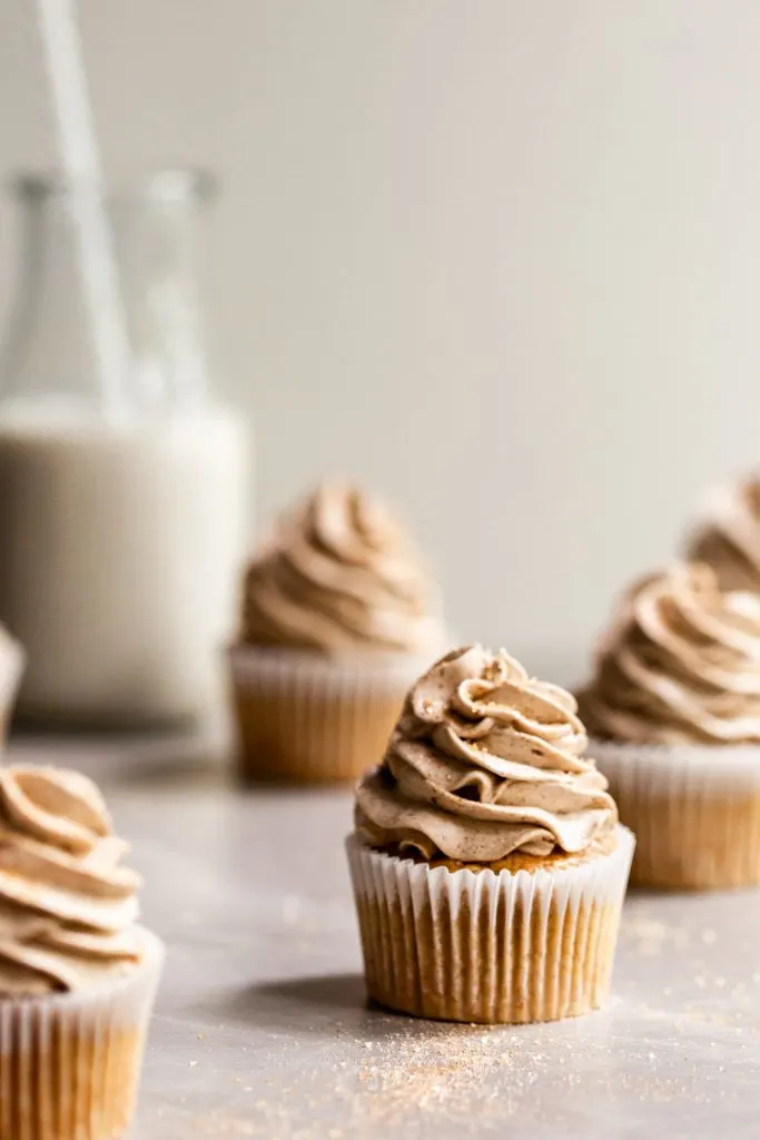 Frosted cupcakes on marble surface covered in cinnamon sugar