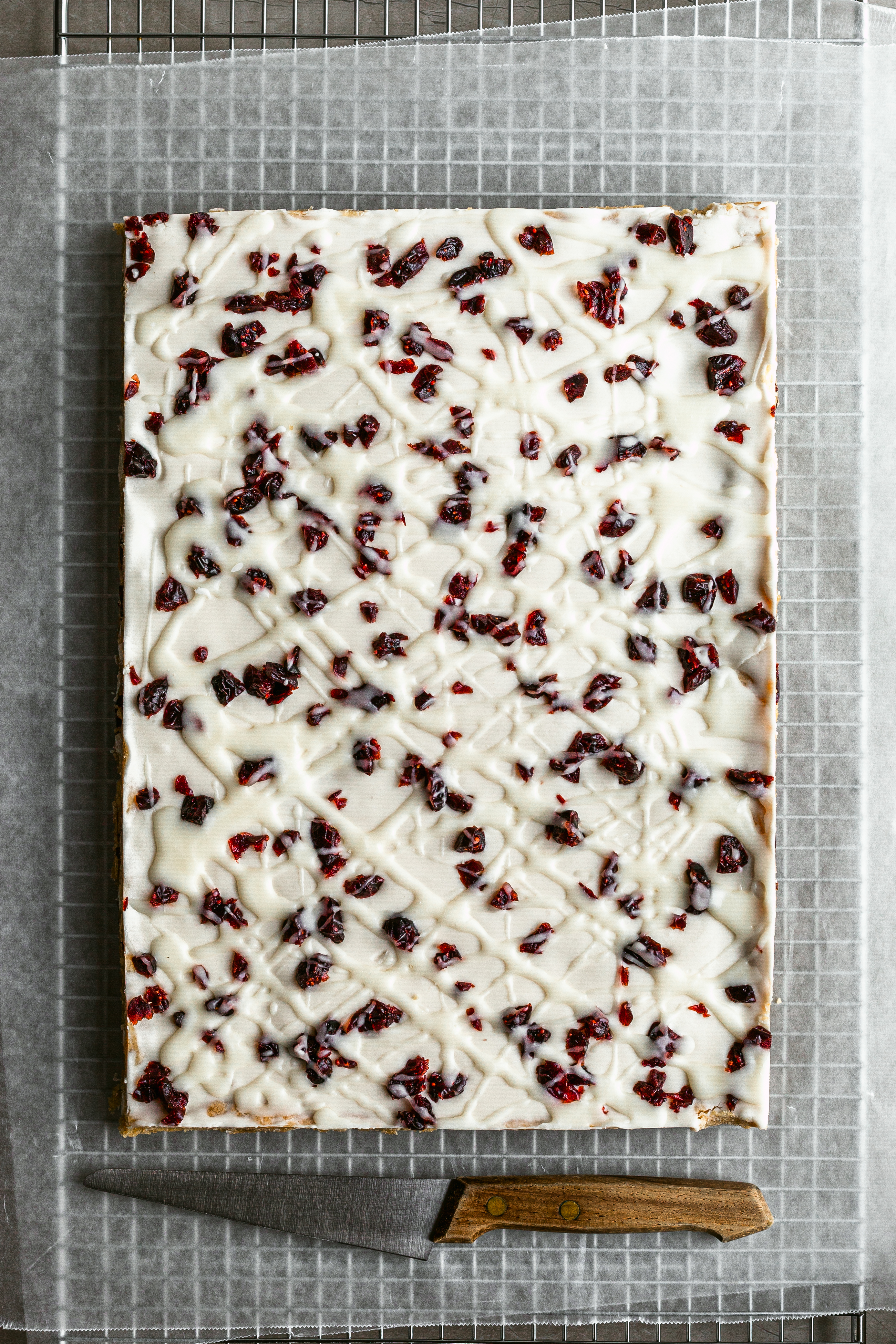 Vegan Bliss Bars flatlay, just before slicing on sheets of parchment paper beside a wood handled knife
