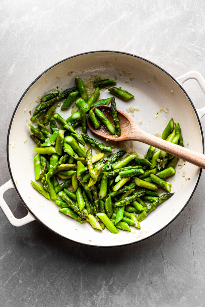 Flat lay of cooked asparagus in a white enamel skilllet